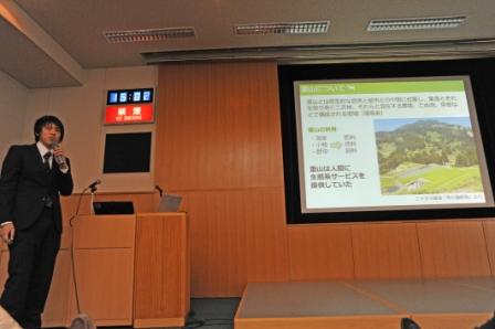 報告会での発表の様子（岐阜大学　土井さん（右上））の画像